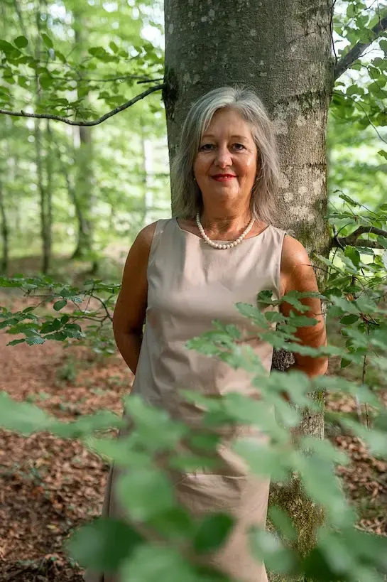 Martina Sedlmair steht im Wald zwischen jungen Buchen